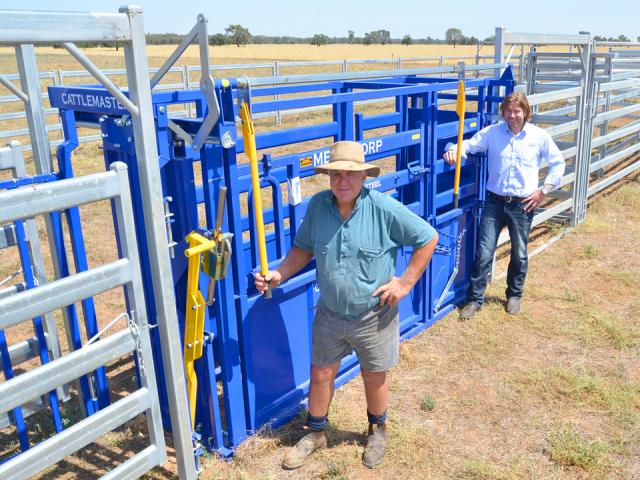 two people standing by an empty blue cattle crush